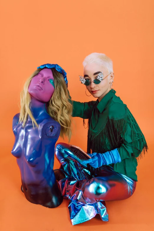 a man and a woman sitting next to each other, an album cover, trending on pexels, antipodeans, holographic suit, bright hair, toys, woman holding another woman