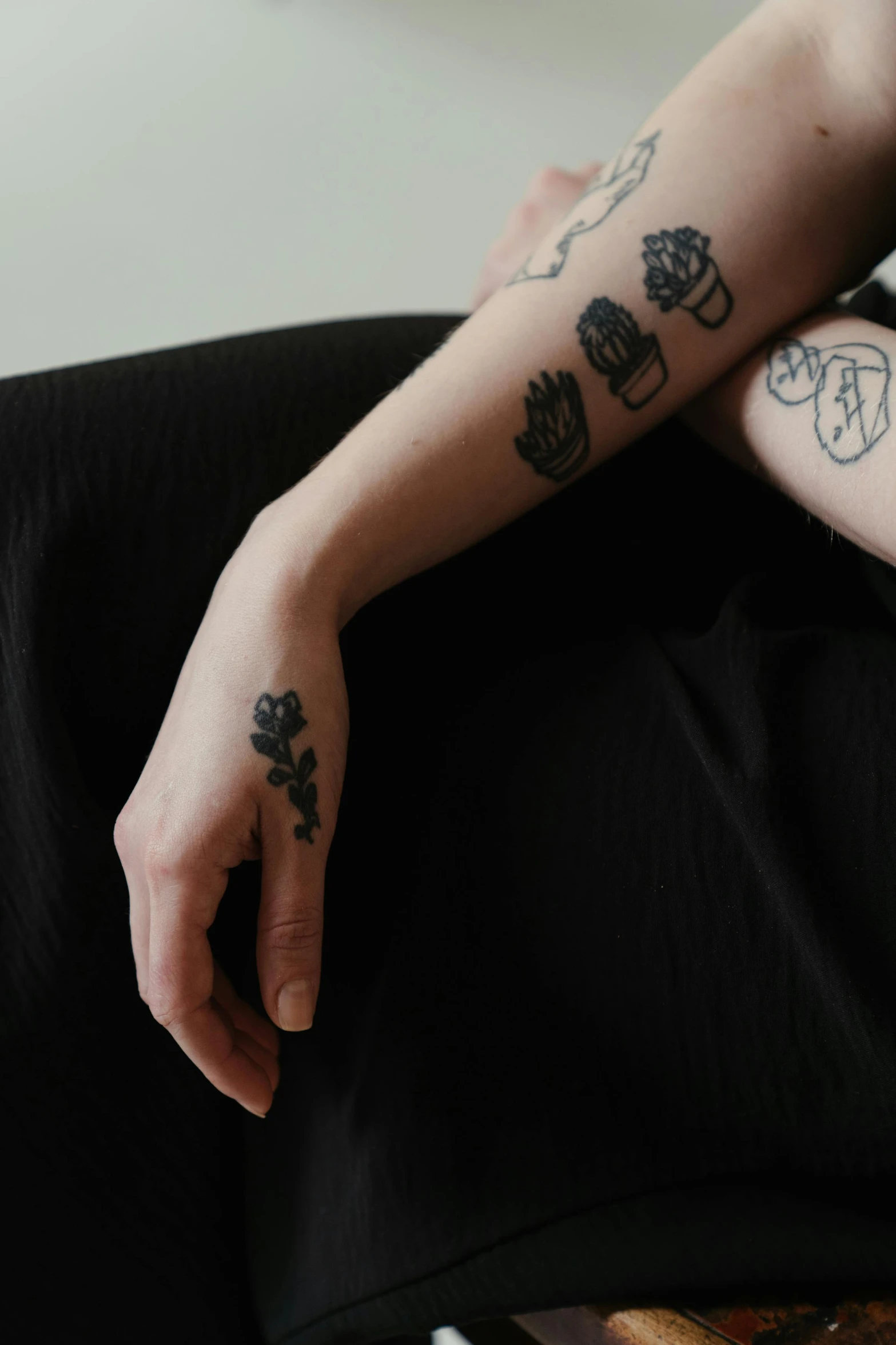 a person sitting on a couch with tattoos on their arms, inspired by Elsa Bleda, trending on pexels, black roses, on a pale background, vessels, black on black