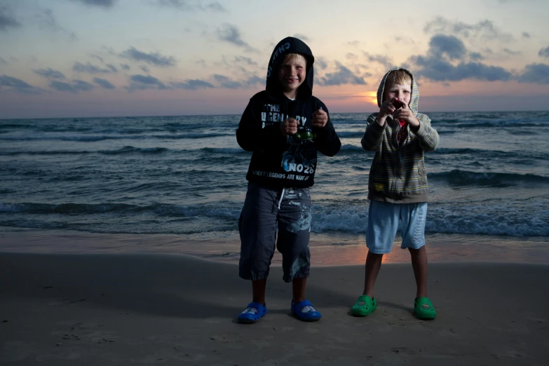 a couple of kids standing on top of a sandy beach, a portrait, by Michael Goldberg, pexels contest winner, israel, avatar image, fishing, close to night