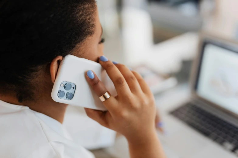 a woman talking on a cell phone in front of a laptop, trending on pexels, white and teal metallic accents, cell cover style, white, ( ( dark skin ) )