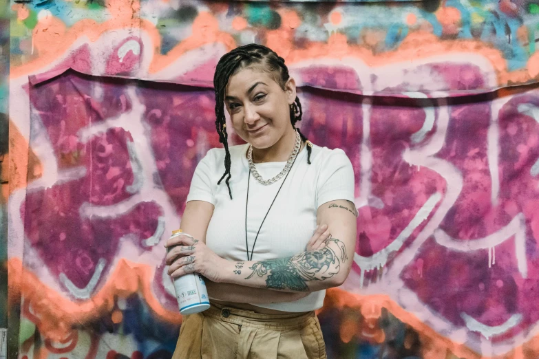 a woman standing in front of a graffiti covered wall, a portrait, by Winona Nelson, pexels contest winner, graffiti, holding a bottle of arak, tattooed, charli xcx, people with mohawks