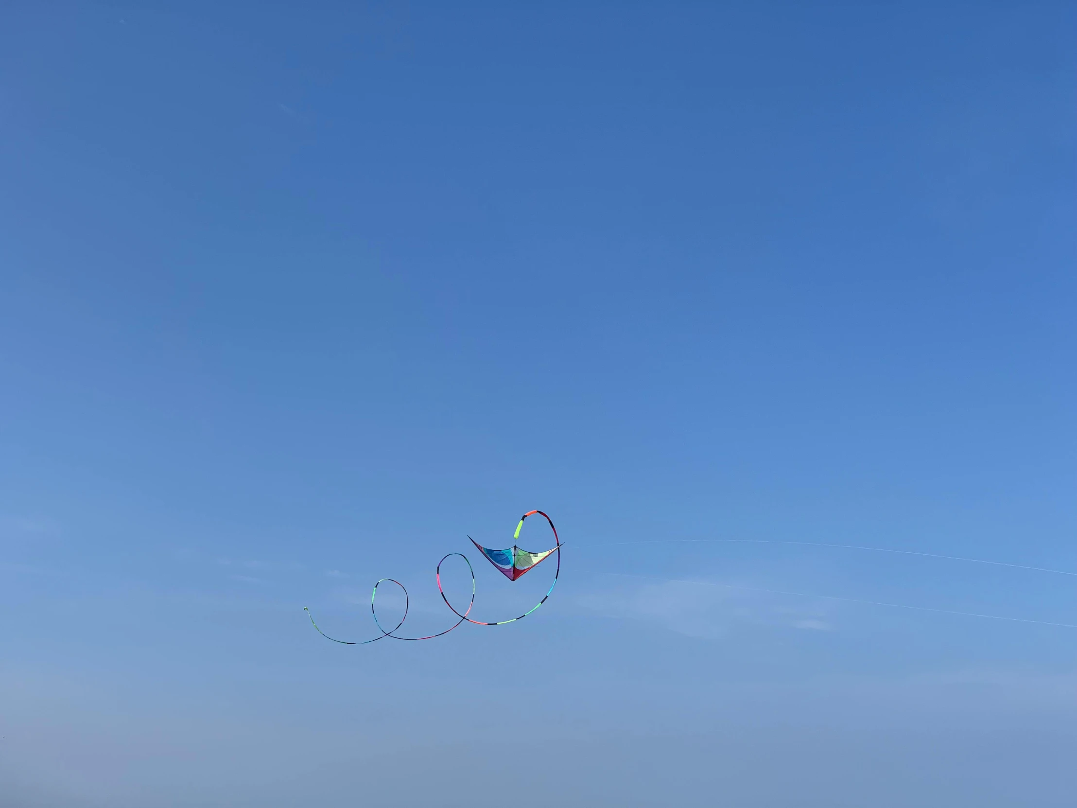 a group of people standing on top of a beach flying kites, clear blue skies, taken with sony alpha 9, dragonfly-shaped, ribbon