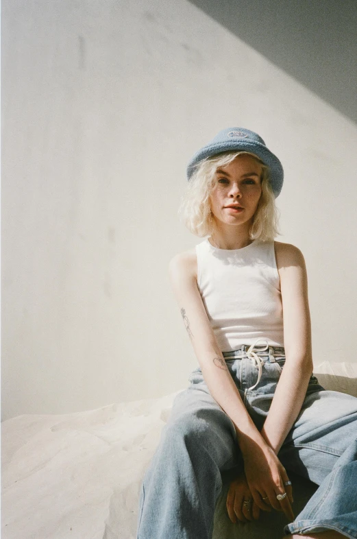 a woman sitting on top of a bed wearing a hat, inspired by Elsa Bleda, trending on pexels, albino hair, baggy jeans, wearing crop top, halfbody headshot