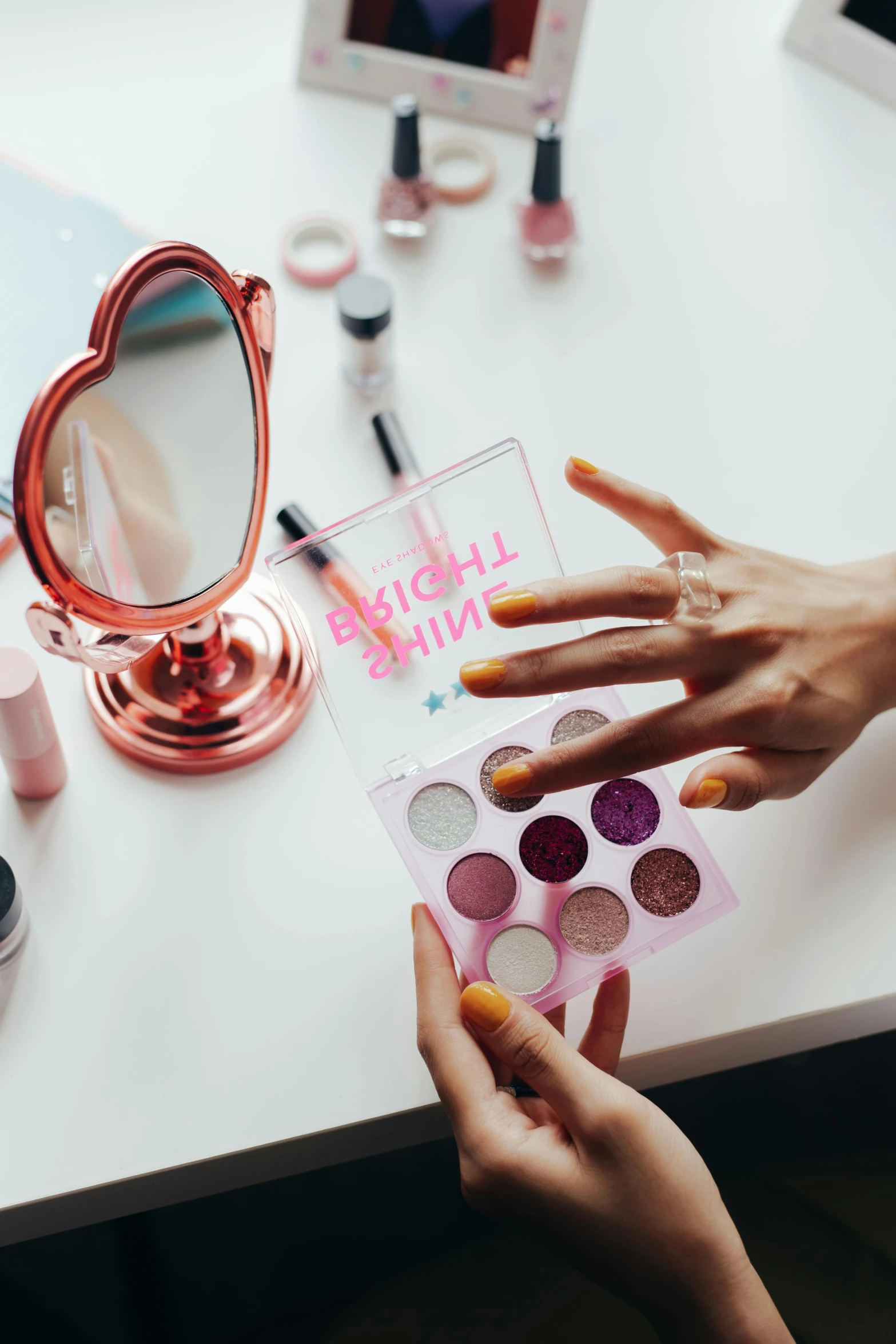 a woman is doing makeup in front of a mirror, by Julia Pishtar, trending on pexels, aestheticism, pink accents, back of hand on the table, acrylic palette, high angle