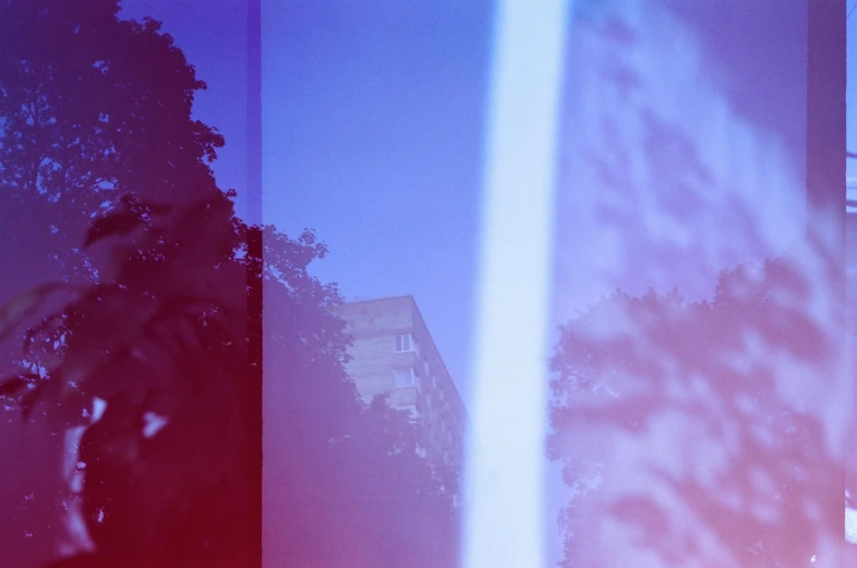 a man walking down a street next to tall buildings, a polaroid photo, unsplash, berlin secession, blue and white and red mist, refracted light, tall purple and pink trees, risograph gradient