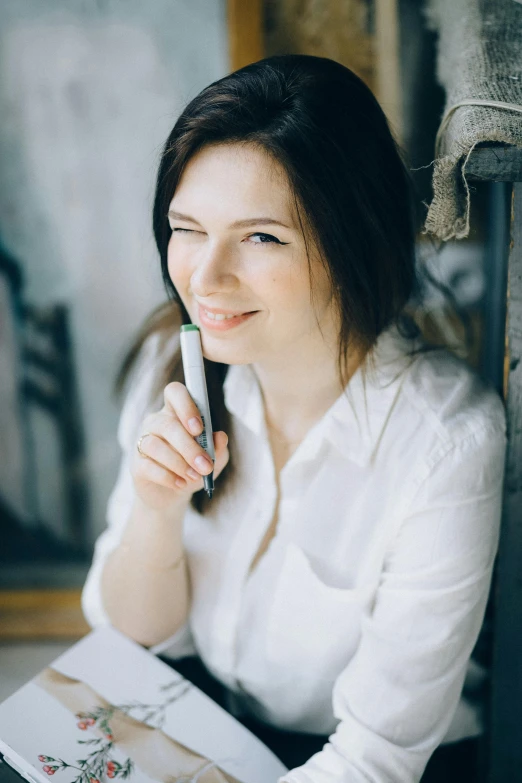 a woman sitting on the floor talking on a cell phone, holding a small vape, moleksandra shchaslyva, headshot profile picture, holding pencil