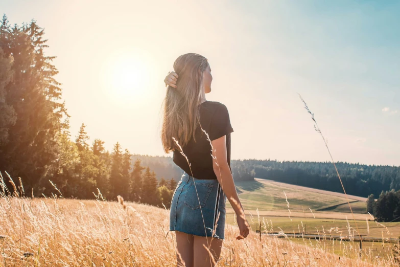 a woman standing in a field of tall grass, pexels contest winner, wearing crop top and miniskirt, sunny landscape, looking out, instagram post