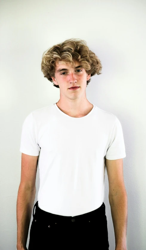 a young man wearing a white shirt and black pants, inspired by John Luke, pexels contest winner, curly blond hair, profile image, promo image, wearing a t-shirt