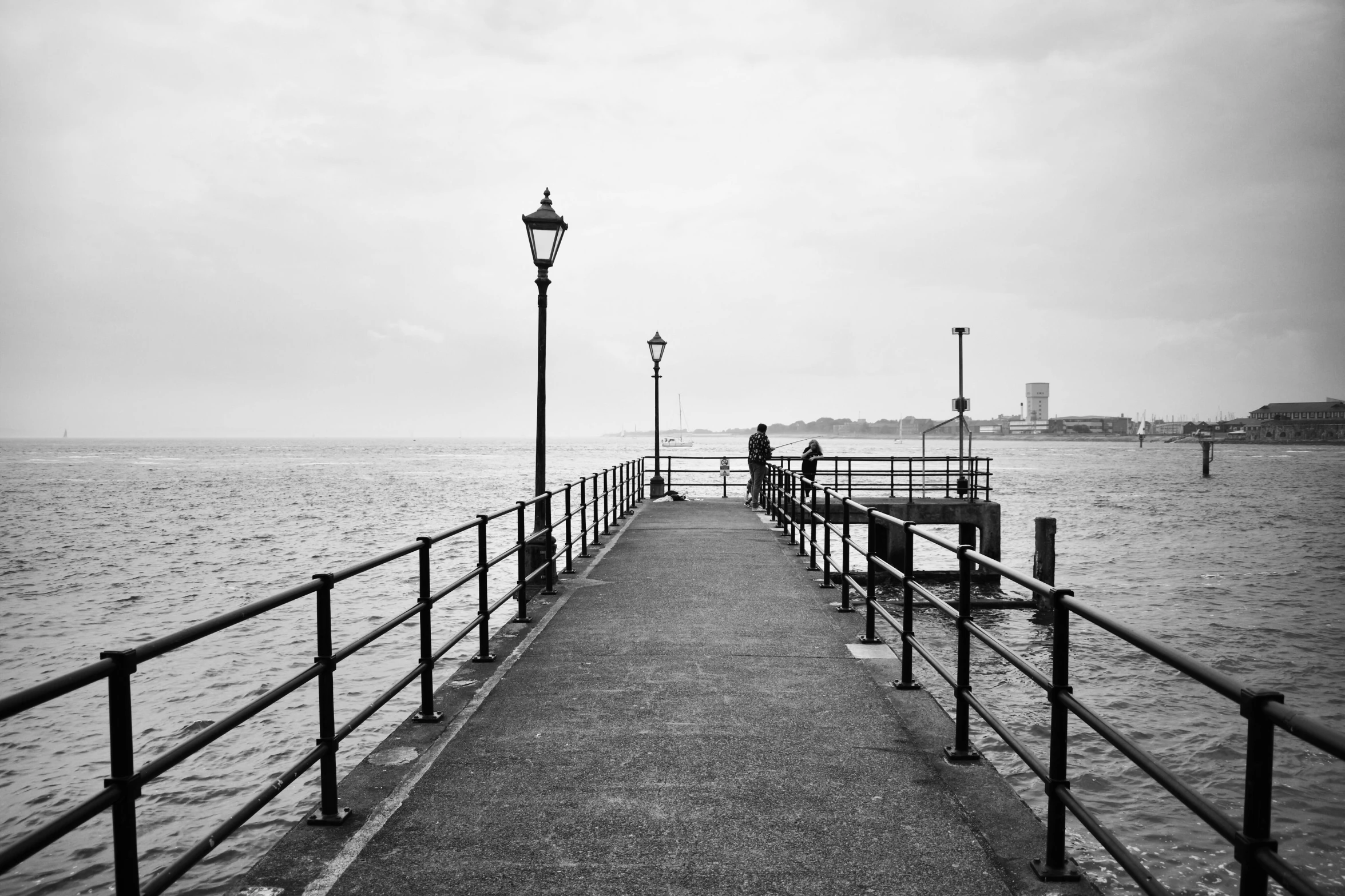 a black and white photo of a pier, a black and white photo, pexels, lamp posts, sad men, overlooking, photographic print