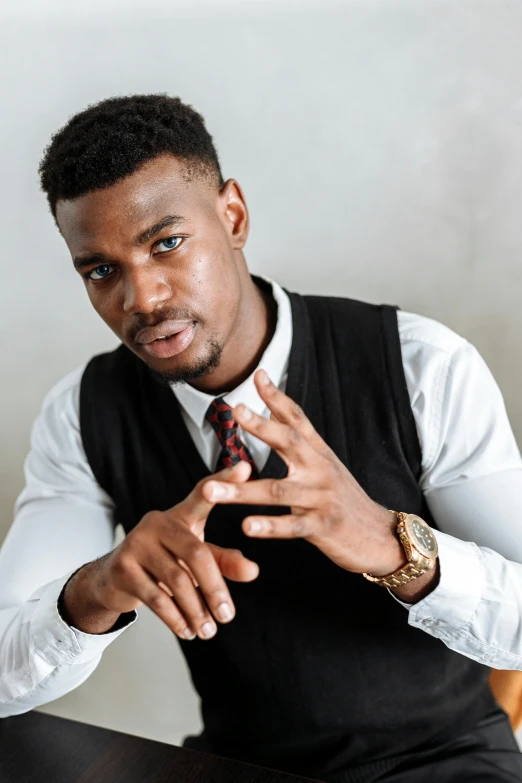 a man in a vest and tie sitting at a table, inspired by Theo Constanté, trending on pexels, renaissance, wakanda, handsome young man, panel of black, solemn gesture