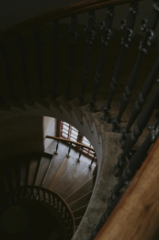 a close up of a spiral staircase in a building, an album cover, pexels contest winner, baroque, low quality footage, high view, dark photo, brown