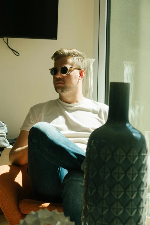 a couple of men sitting on top of a couch, an album cover, by Jacob Toorenvliet, trending on reddit, wearing shades, holding a bottle, standing near a window, one man is blond