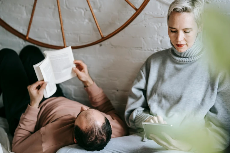 a man and woman sitting on a bed reading a book, pexels contest winner, acupuncture treatment, relaxed dwarf with white hair, relaxing on a couch, head down