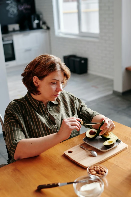 a woman sitting at a table cutting an avocado, inspired by Caro Niederer, pexels contest winner, contemplation, plating, low quality photo, russian