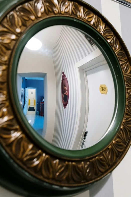 a close up of a mirror on a wall, inspired by Wes Anderson, art nouveau, an escape room in a small, fisheye camera, narrow hallway, color photograph