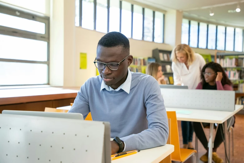 a man sitting at a desk in front of a computer, pexels contest winner, academic art, adut akech, librarian, in a school classroom, lachlan bailey