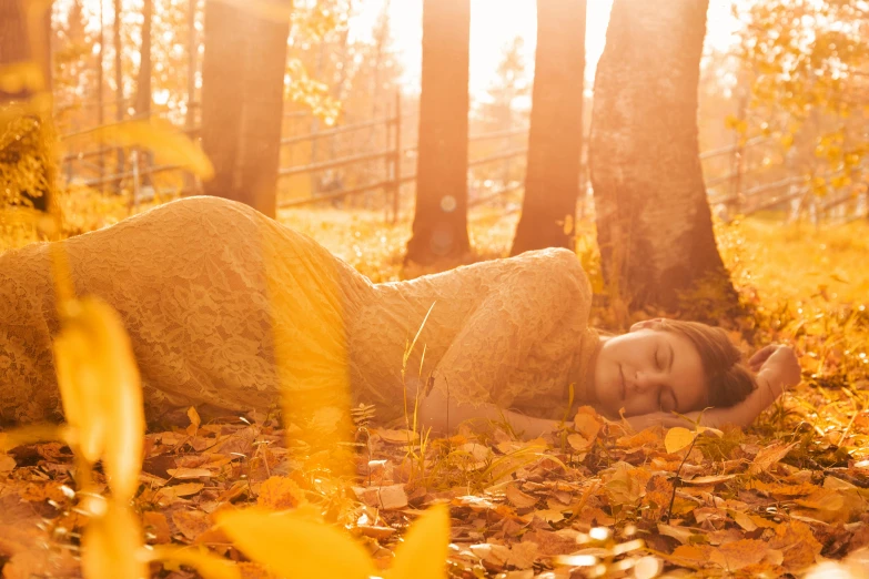 a woman that is laying down in the leaves, inspired by Oleg Oprisco, unsplash, backlit golden hour, yellow, medium-shot, october