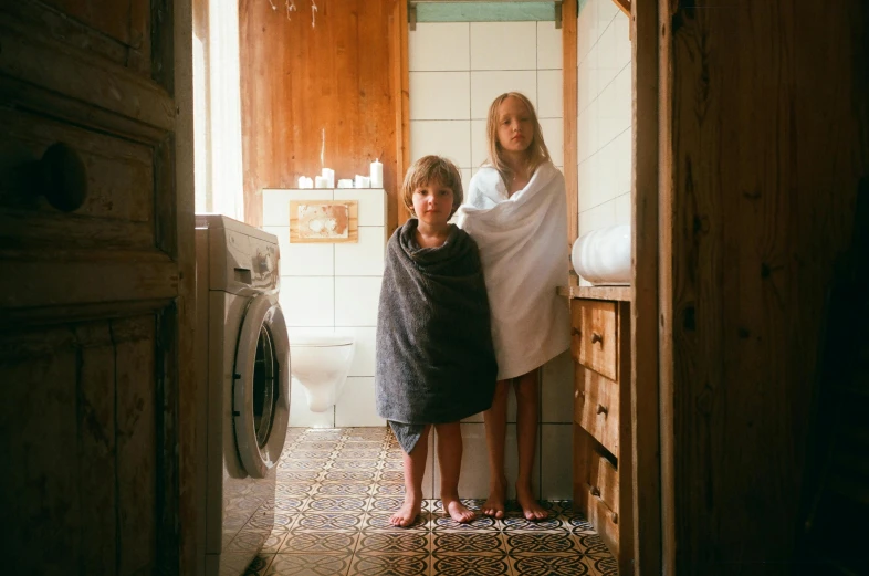 a couple of women standing next to each other in a bathroom, by Emma Andijewska, unsplash contest winner, kids, towels, boy and girl, cottagecore