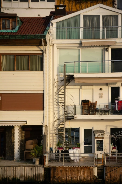 a group of buildings next to a body of water, inspired by Ricardo Bofill, unsplash, modernism, awnings, balcony door, japan shonan enoshima, from street level