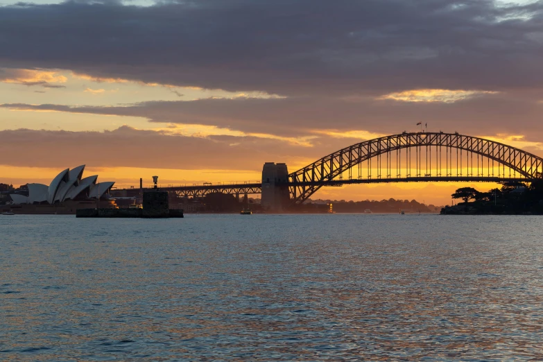 a large body of water with a bridge in the background, inspired by Sydney Carline, pexels contest winner, sunset panorama, fan favorite, harbour, ochre