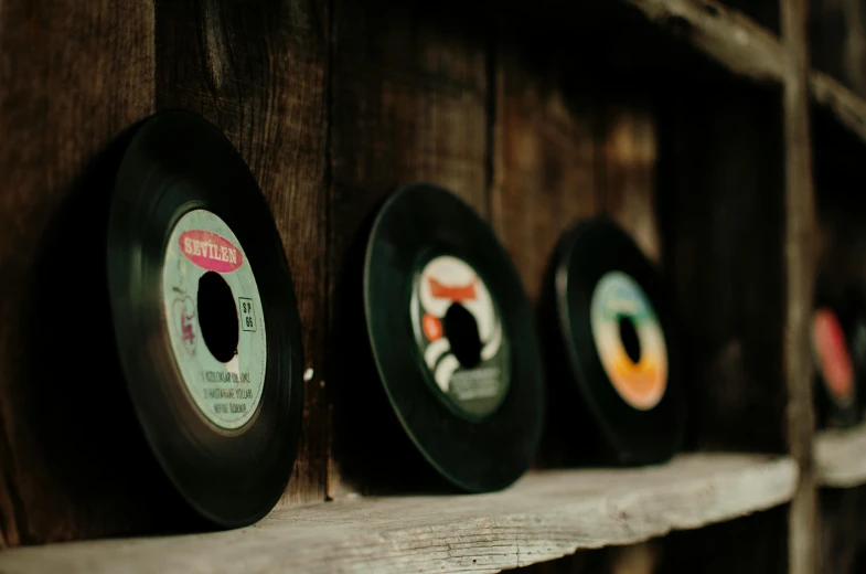 a row of records sitting on top of a wooden shelf, pexels contest winner, graffiti, singer songwriter, round format, 1 2 9 7, old color photograph