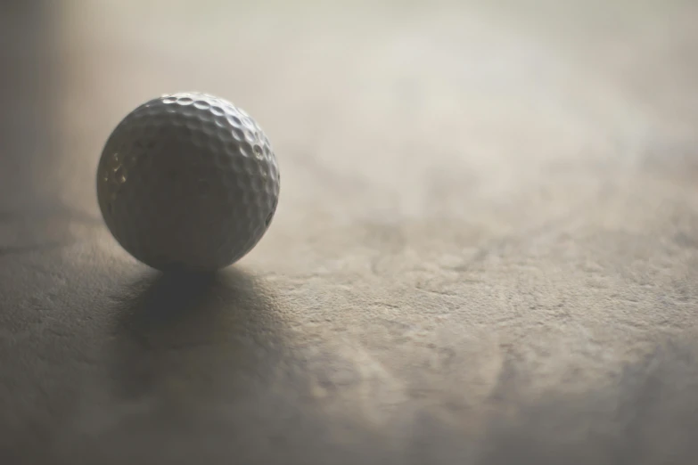 a close up of a golf ball on a table, by Adam Marczyński, unsplash, photorealism, 15081959 21121991 01012000 4k, sepia toned, marble hole, shallow depth of field