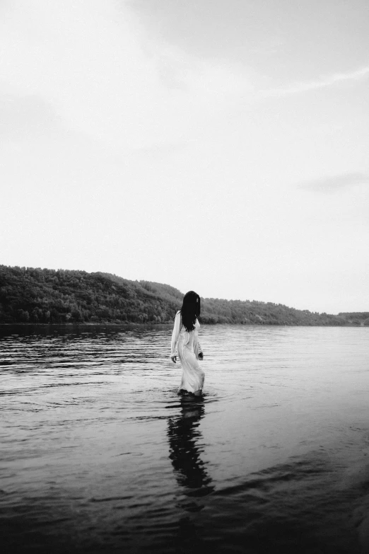 a woman standing in a body of water, a black and white photo, inspired by Elsa Bleda, unsplash, ✨🕌🌙, great river, beautiful lonely girl, lowres