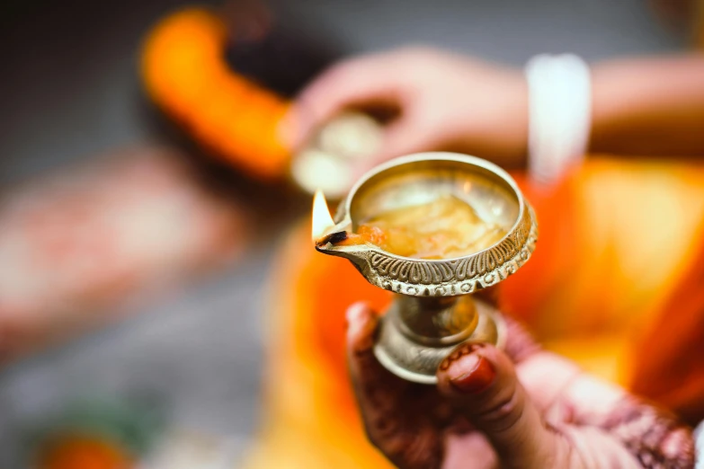 a close up of a person holding a cup, hurufiyya, hinduism, avatar image, amber jewelry, thumbnail