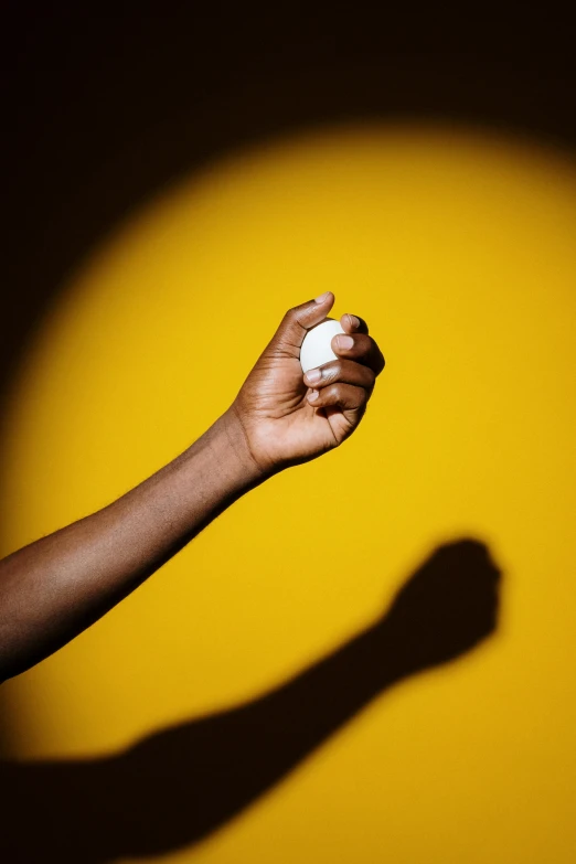 a person holding a baseball in their hand, by Andrew Domachowski, visual art, yellow light, ( ( dark skin ) ), foam, soft shadow