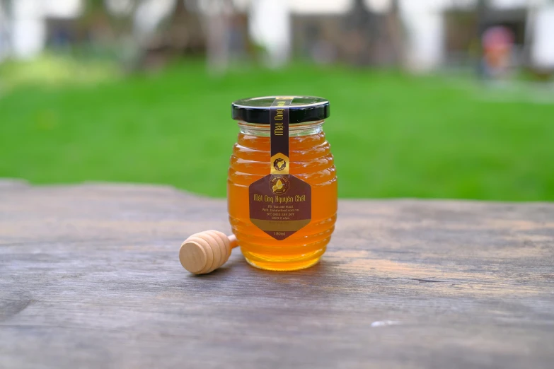 a jar of honey sitting on top of a wooden table, bangalore, medium wide front shot, majestic pose, bee