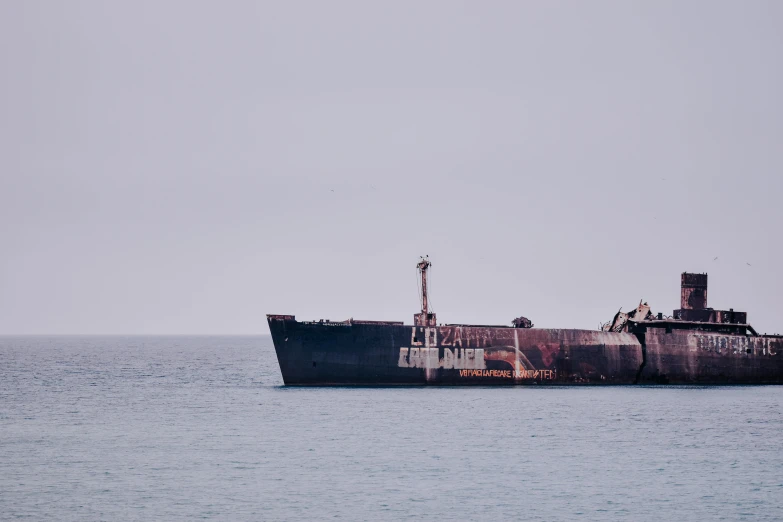 a large ship sitting in the middle of the ocean, by Elsa Bleda, a photograph of a rusty, low iso, black, former