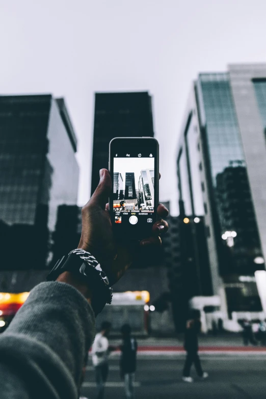 a person holding up a smart phone in the middle of a city, pexels contest winner, hypermodernism, towering over the camera, tech-noir, iphone video, color picture