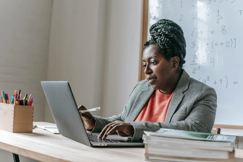 a woman sitting at a desk using a laptop computer, by Carey Morris, pexels contest winner, aida muluneh, riyahd cassiem, high quality screenshot, amanda lilleston