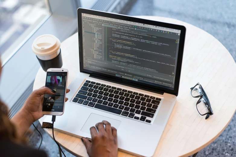 a person sitting at a table with a laptop and cell phone, developers, thumbnail, multiple stories, brown