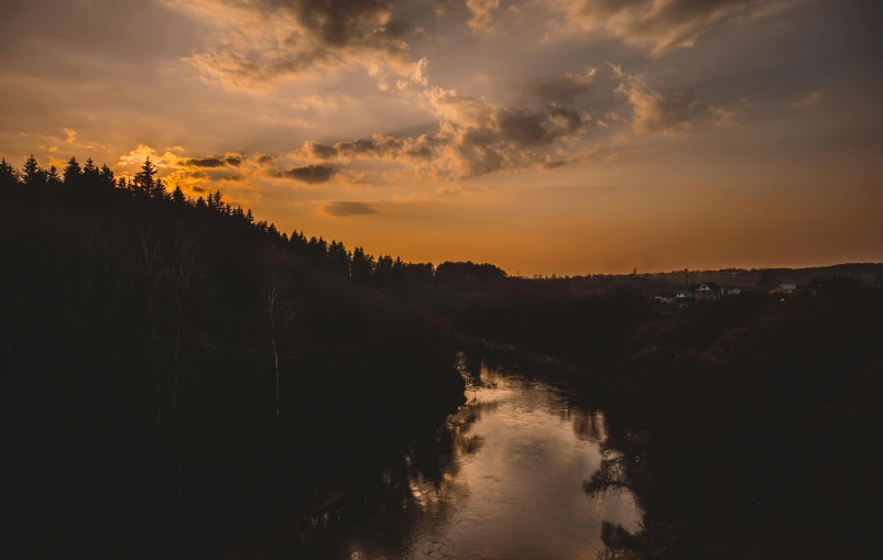 a river running through a forest under a cloudy sky, a picture, pexels contest winner, romanticism, orange lit sky, a high angle shot, sunset photo, brown