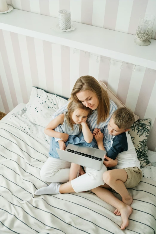 a woman and two children on a bed with a laptop, pexels contest winner, striped, instagram post, ekaterina, kids movie