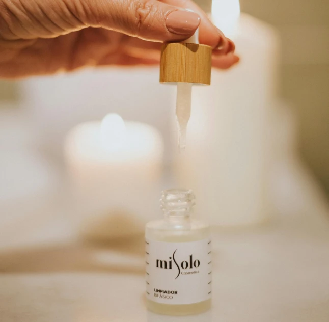 a close up of a person holding a bottle of liquid, by Miyamoto, trending on unsplash, candle dripping white wax, photoshoot for skincare brand, apollo, product display photograph