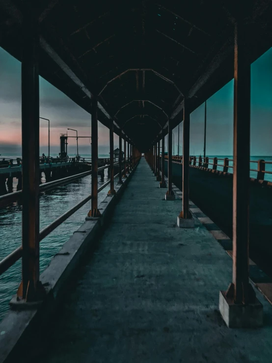 a long walkway next to a body of water, inspired by Elsa Bleda, unsplash contest winner, very dark and abandoned, teal aesthetic, harbor, instagram post
