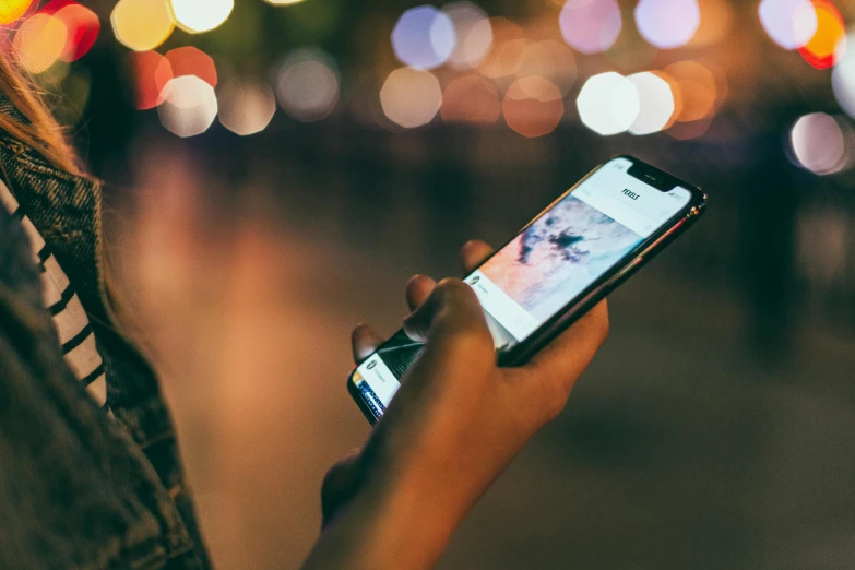 a close up of a person holding a cell phone, a picture, trending on pexels, happening, it's night time, getty images, instagram post, looking sideways