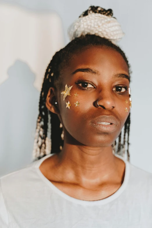 a woman with gold stars on her face, trending on pexels, afrofuturism, skinny face, ☁🌪🌙👩🏾, androgynous male, ( ( brown skin ) )