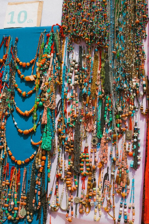 a bunch of necklaces hanging on a wall, teal and orange colors, nepal, split near the left, lots of shops