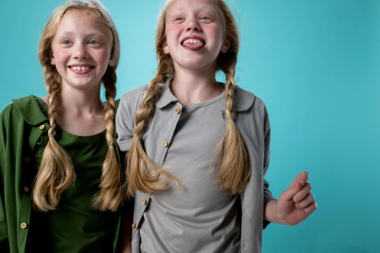 a couple of young girls standing next to each other, pexels contest winner, teal studio backdrop, extra teeth, long pigtail, gemmy woud binnendijk