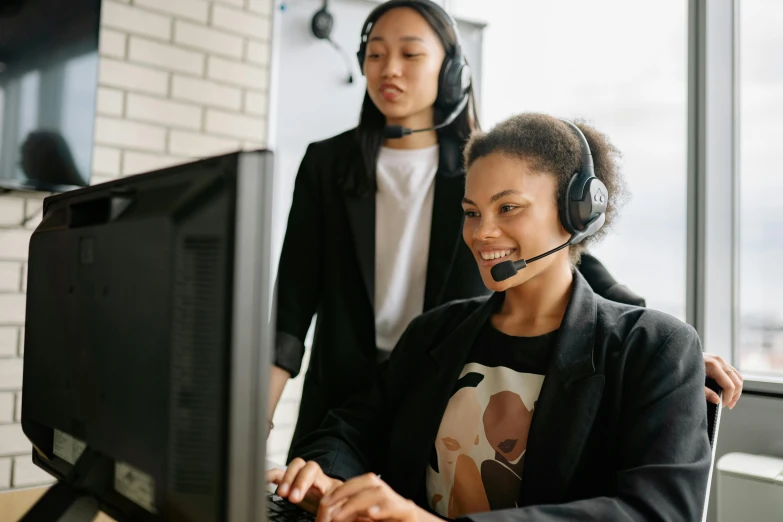 a woman sitting in front of a computer wearing a headset, trending on pexels, medium shot of two characters, manuka, black, staff