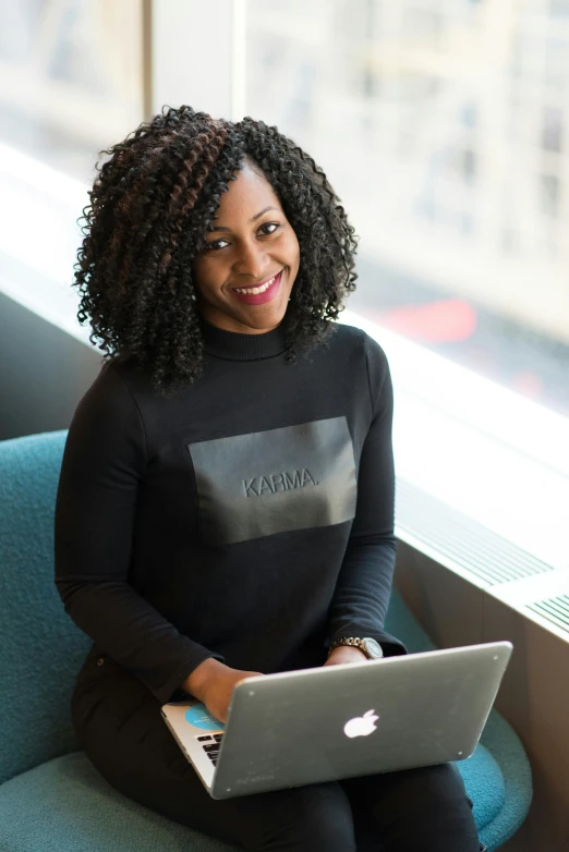 a woman sitting on a couch with a laptop, qiyana, vp of marketing, karma, pictured from the shoulders up