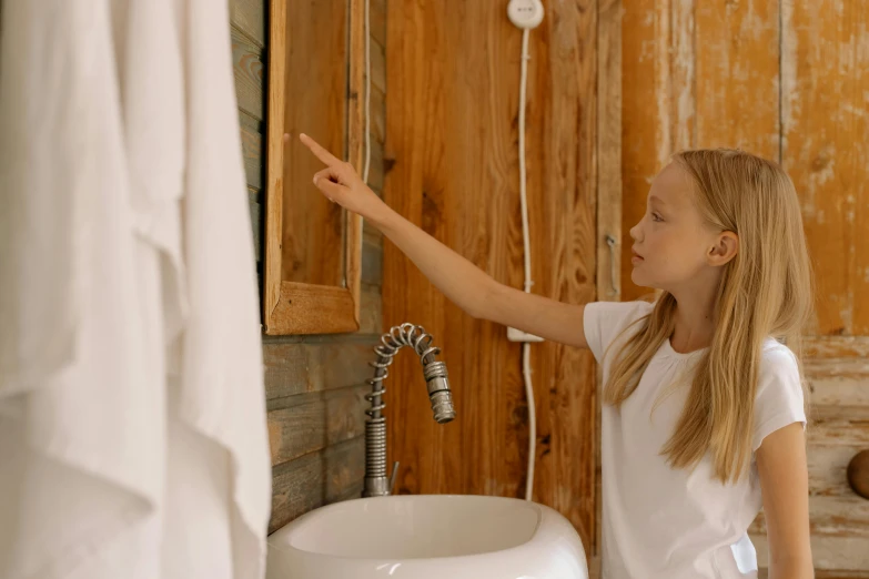 a little girl pointing at a faucet in a bathroom, pexels contest winner, in a cabin, profile image, teenage girl, a blond