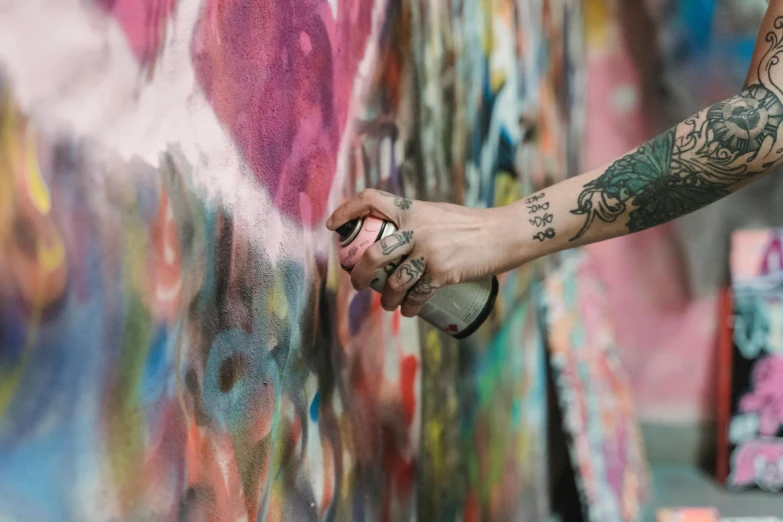 a person spray painting graffiti on a wall, inspired by Sam Spratt, trending on pexels, with tattoos, multi - coloured, hand, plain background