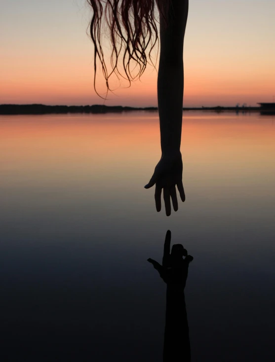 a person standing in front of a body of water, unsplash, art photography, hands reaching for her, sean yoro, ((sunset)), hanging upside down