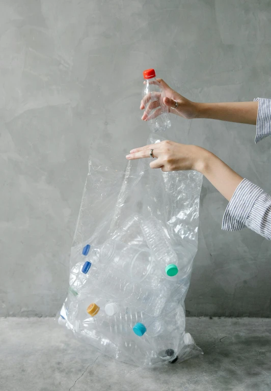 a woman holding a plastic bottle in one hand and a plastic bag in the other, an album cover, by Julia Pishtar, pexels contest winner, plasticien, marbles, sustainable materials, squishy, jakarta