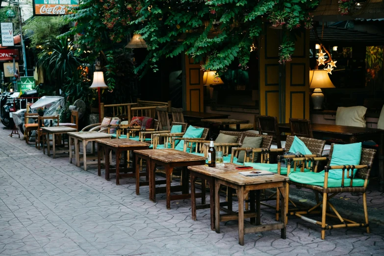 a row of wooden tables sitting on top of a sidewalk, unsplash, art nouveau, humid evening, armchairs, tehran, restaurant menu photo