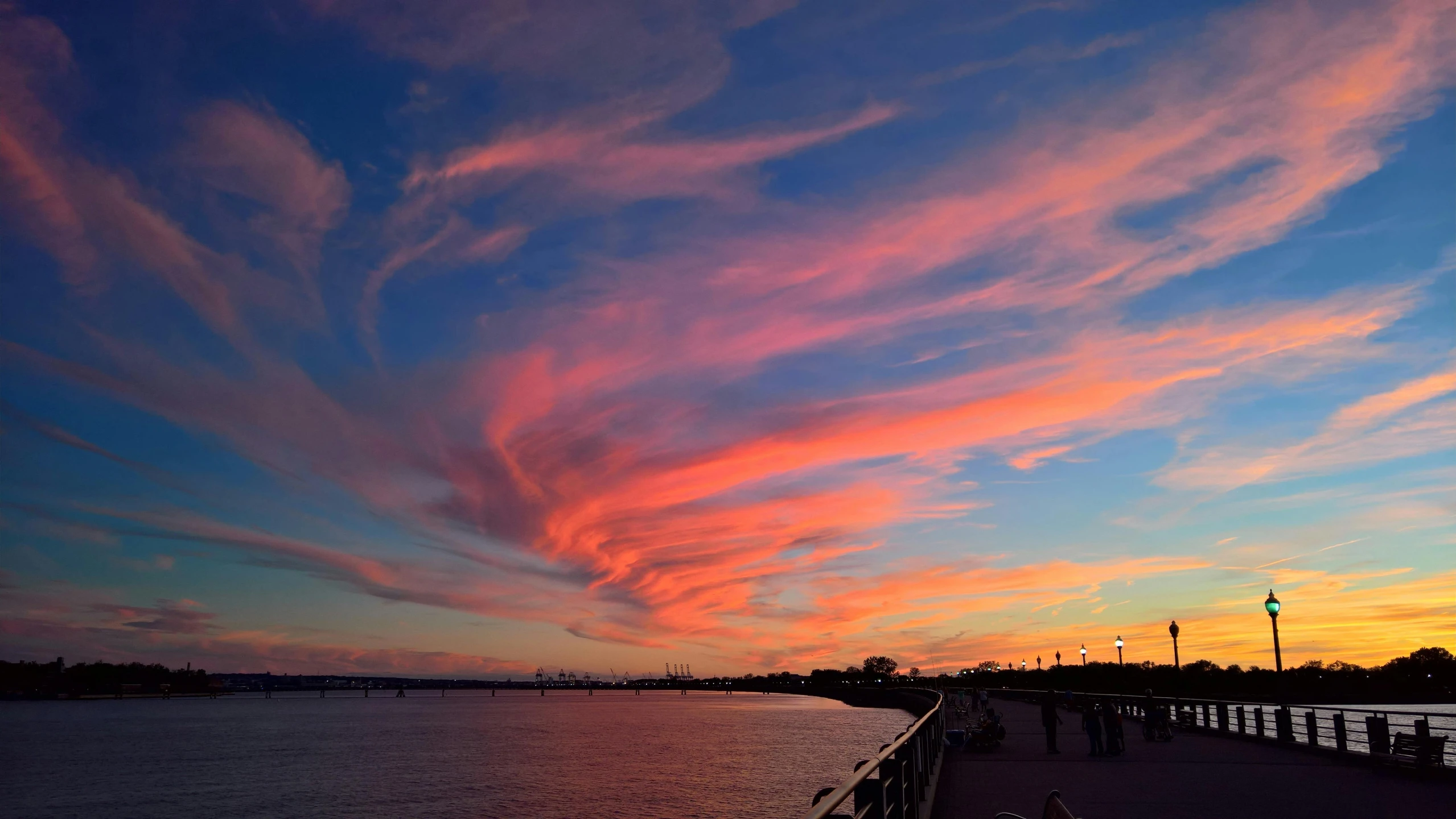 a pier that is next to a body of water, by Susy Pilgrim Waters, pexels contest winner, romanticism, colorful clouds, redpink sunset, swirly clouds, city sunset